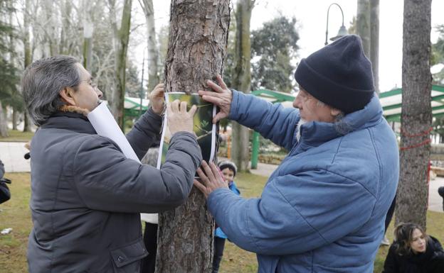 Dos personas colocan carteles para protestar contra la tala de árboles en Los Jardinillos. 