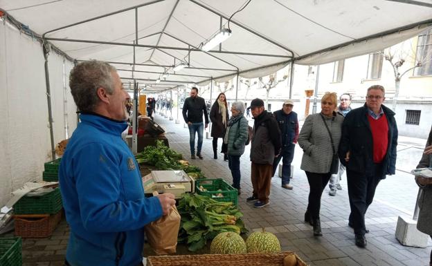 Un grupo de personas observa los puestos del Ecomercado. 