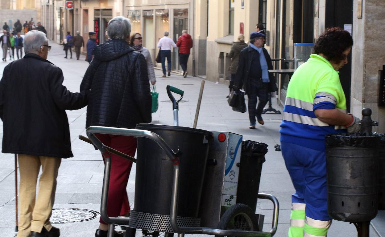 Una operaria del servicio de limpieza retira los desechos de una papelera de la Calle Real. 