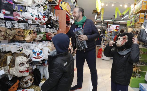 Un niño se prueba una máscara de un gorila, miesntras otro niño y un adulto observan otros artículos en la juguetería Andérez de la capital.