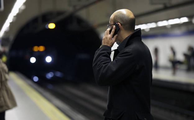 Gente habla por teléfono móvil en una estación del metro de Madrid. 