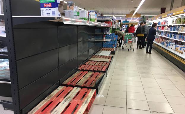 Imagen principal - El espacio destinado a las cajas de leche, vacío en un gran superficie de la capital vallisoletana. Abajo a la izquierda, el estante del papel higiénico, casi vacío, en un supermercado del polígono de Argales y Varios operarios reabastecen el aceite en otro supermercado del barrio de Parquesol. 