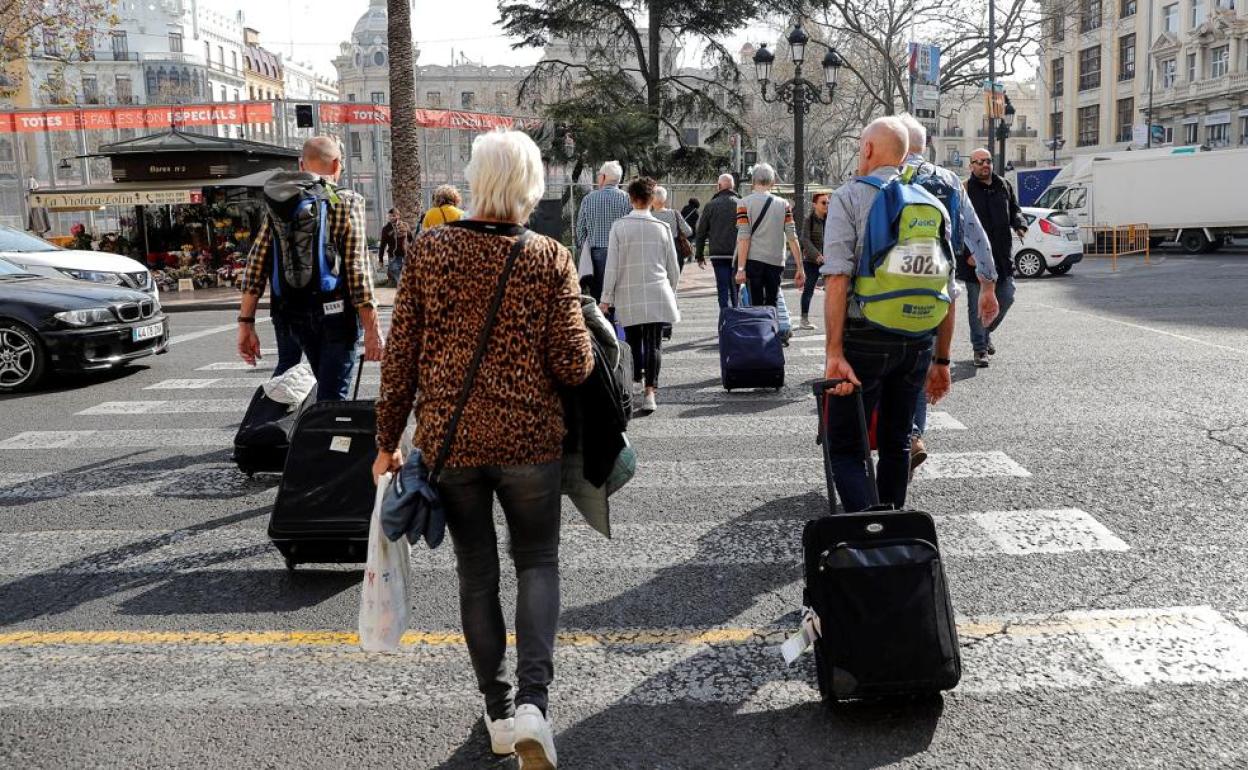 Un grupo de turistas recién llegados a Valencia cruzan por la céntrica plaza del Ayuntamiento 