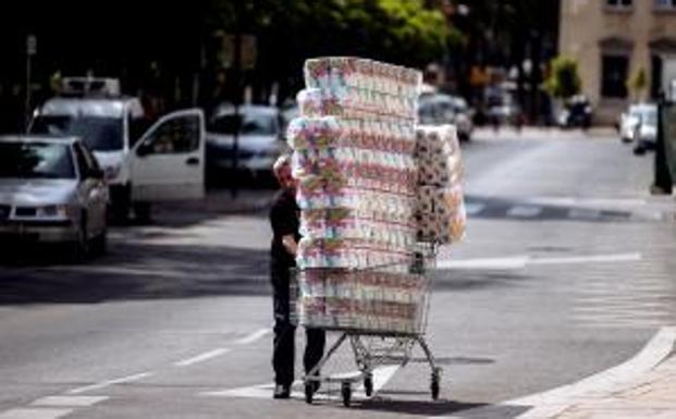 Un trabajador transporta numerosos rollos de papel higiénico en un carro de la compra. 