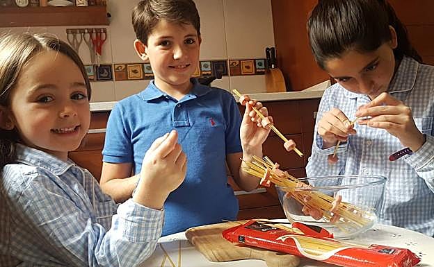 Lola, Sito e Inés Velasco pinchando los espagueti entre las salchichas para preparar el plato de pasta