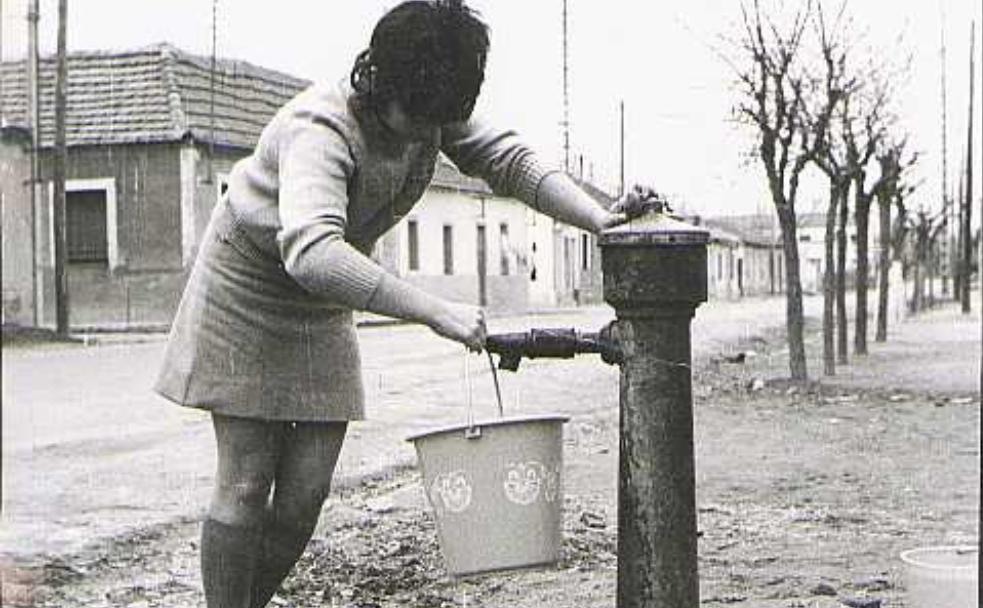 Una mujer llena un caldero de agua en la fuente de la calle de las Arcas Reales, donde en febrero de 1922 se cometió el crimen.