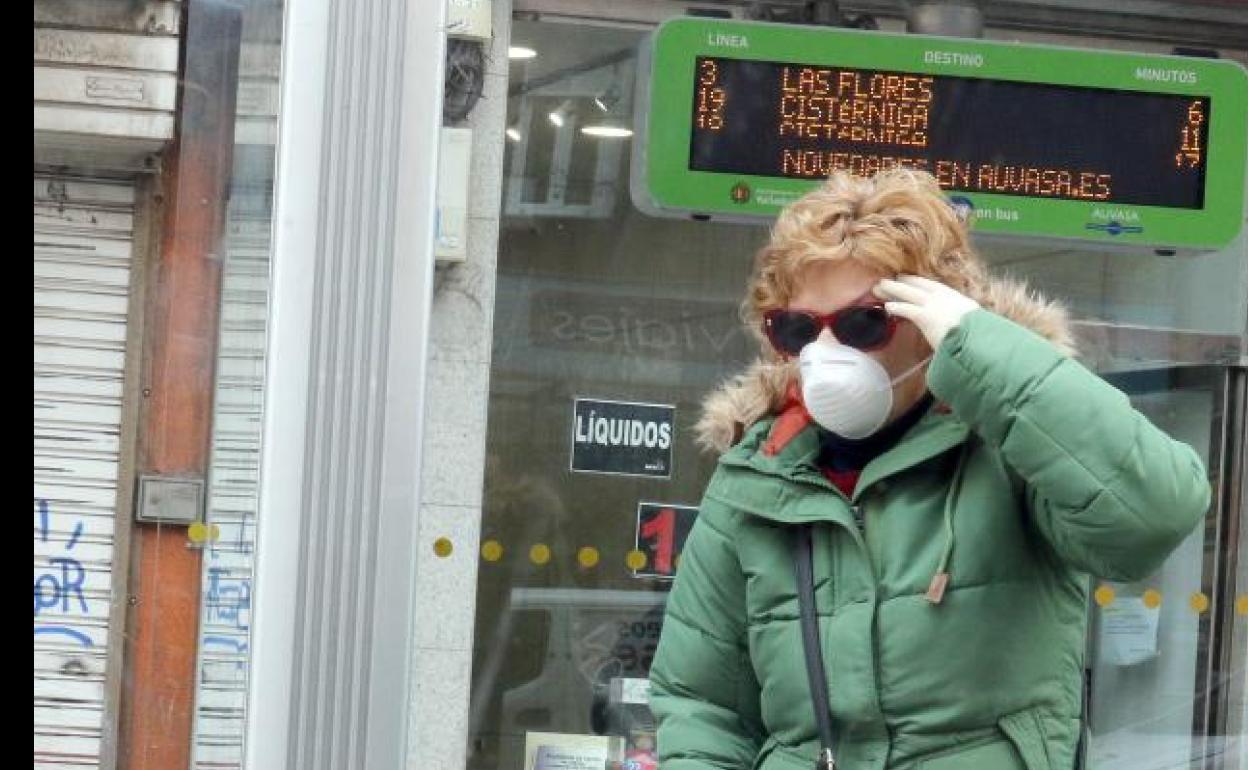 Una mujer espera al autobús en Valladolid con una mascarilla. 