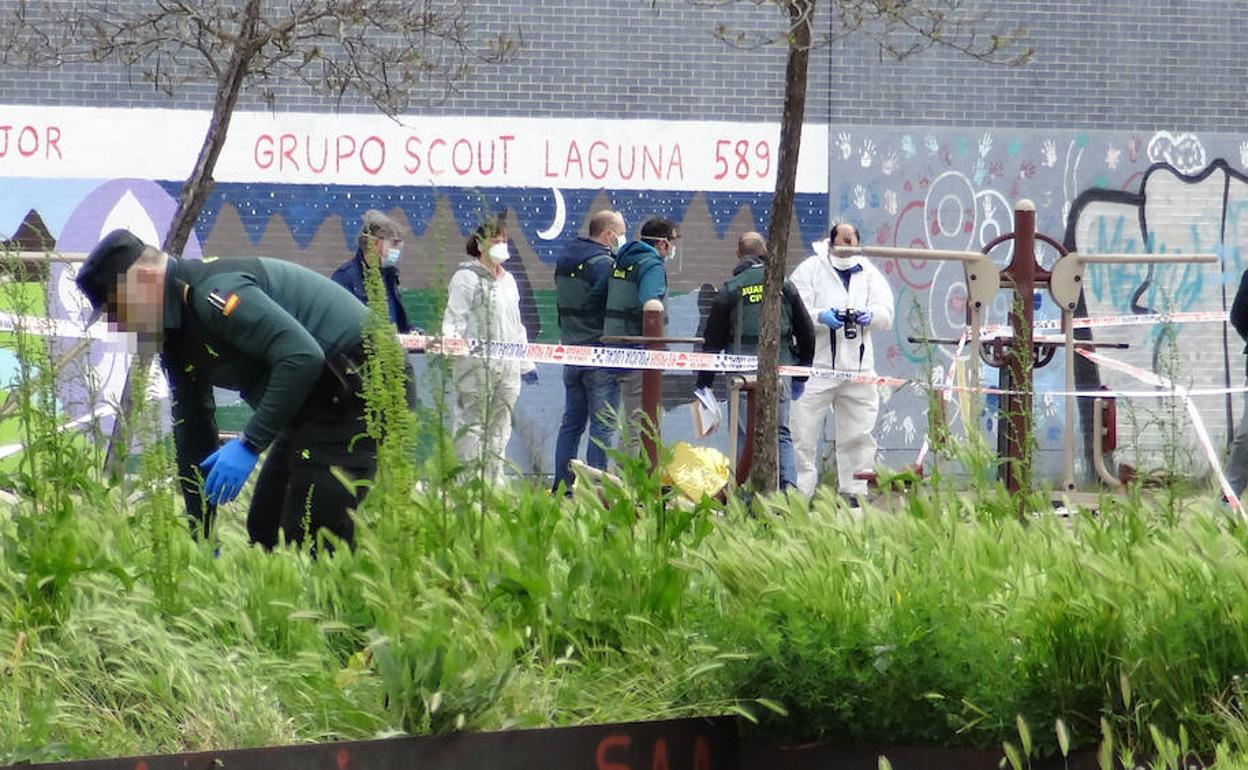 Los especialistas de la Guardia Civil inspeccionan el escenario, al fondo, antes del traslado del cuerpo de la víctima. Un agente, en primer término, busca pruebas entre la vegetación del parque de Laguna.