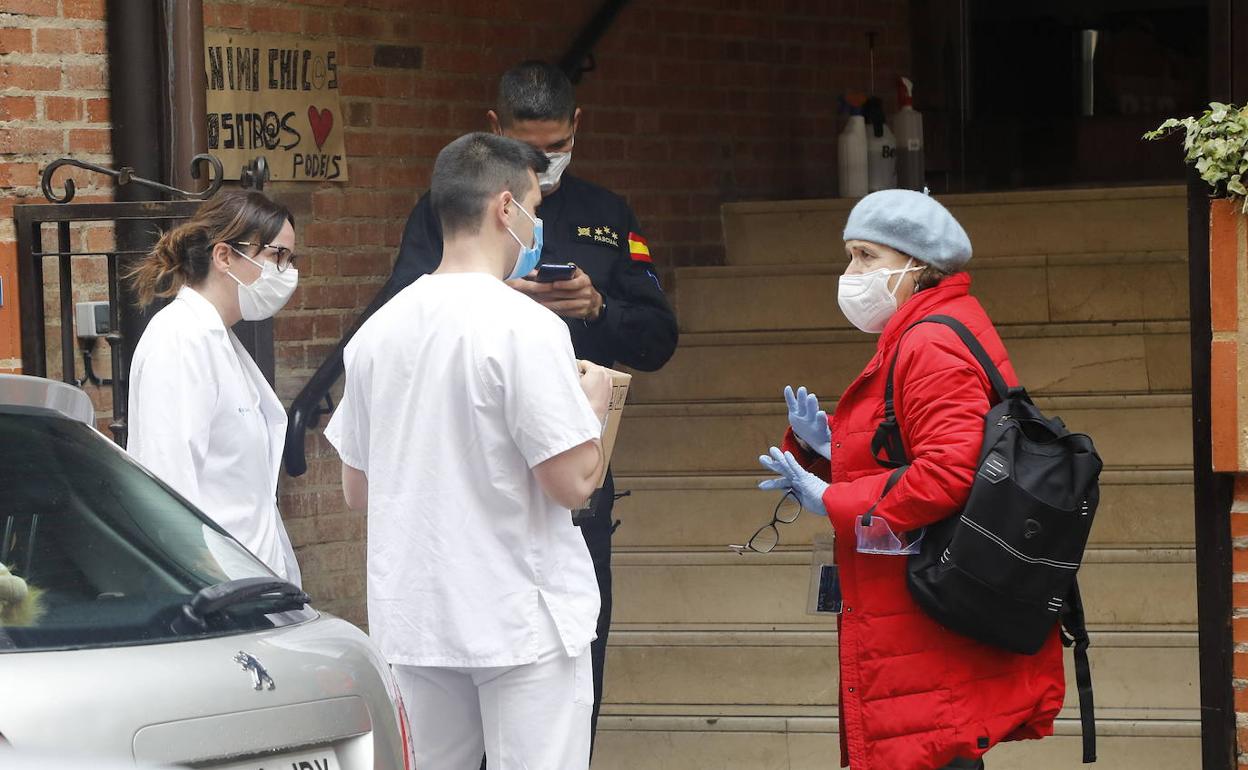 Dos sanitarios y un policía atienden las preguntas de una mujer.