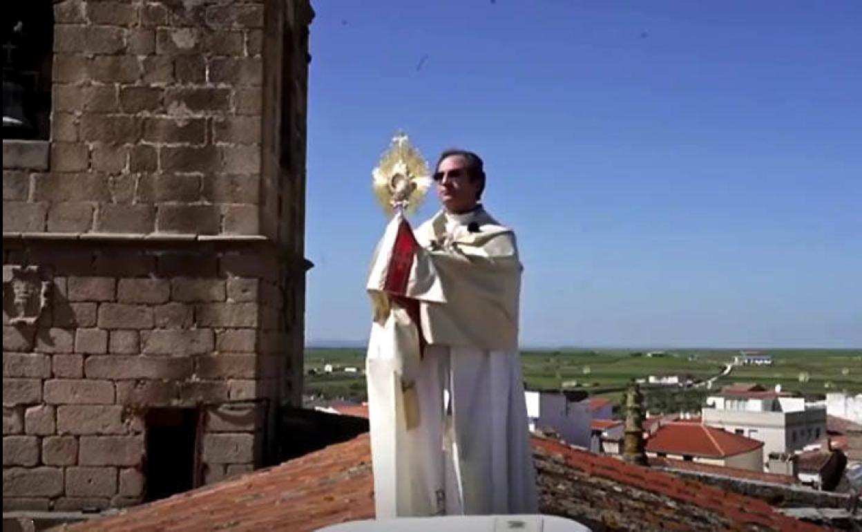 El párroco de Arroyo de la Luz bendice con el Santísimo desde el tejado de la iglesia por las víctimas de la covid-19.