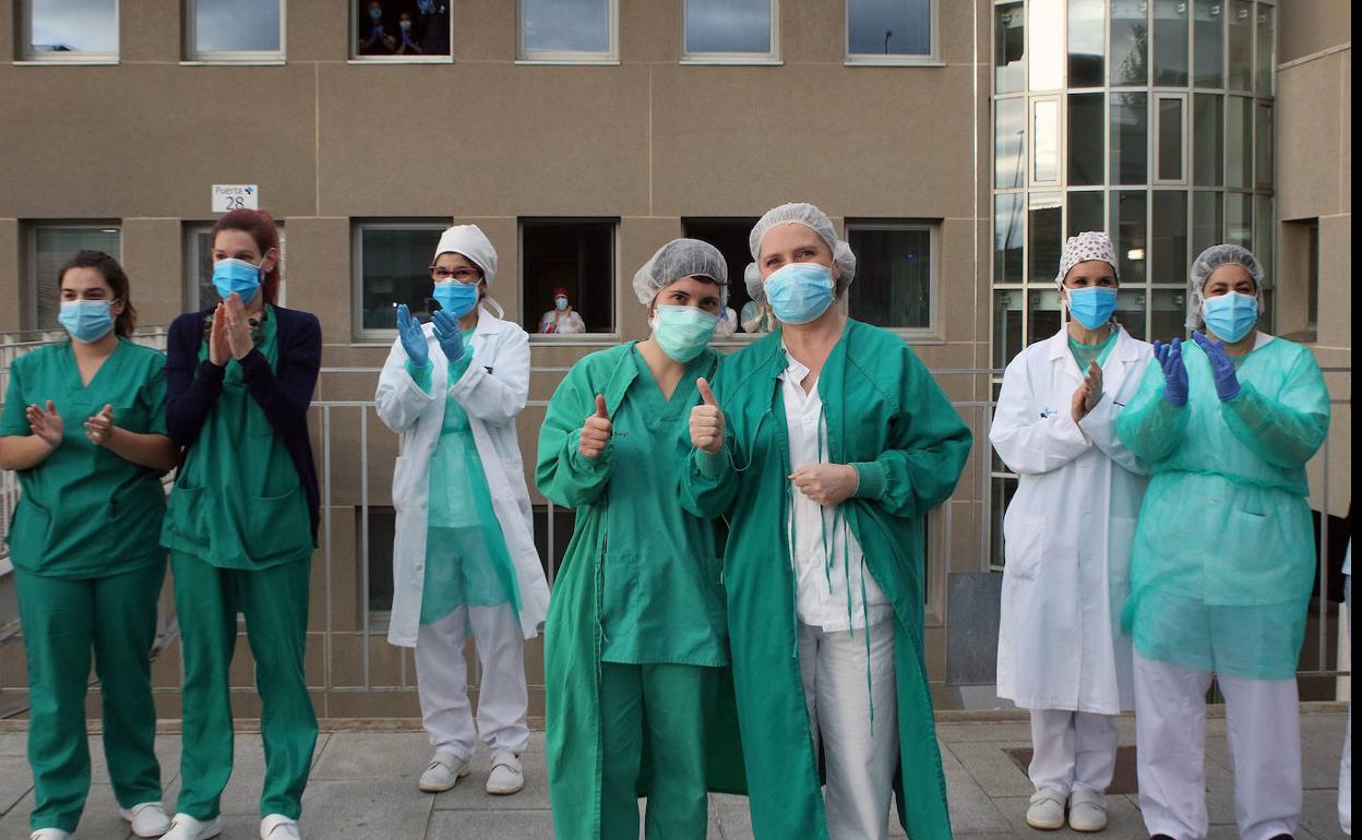 Dos integrantes de la UCI levantan el pulgar ante los aplausos de otros sanitarios del Hospital General de Segovia. 