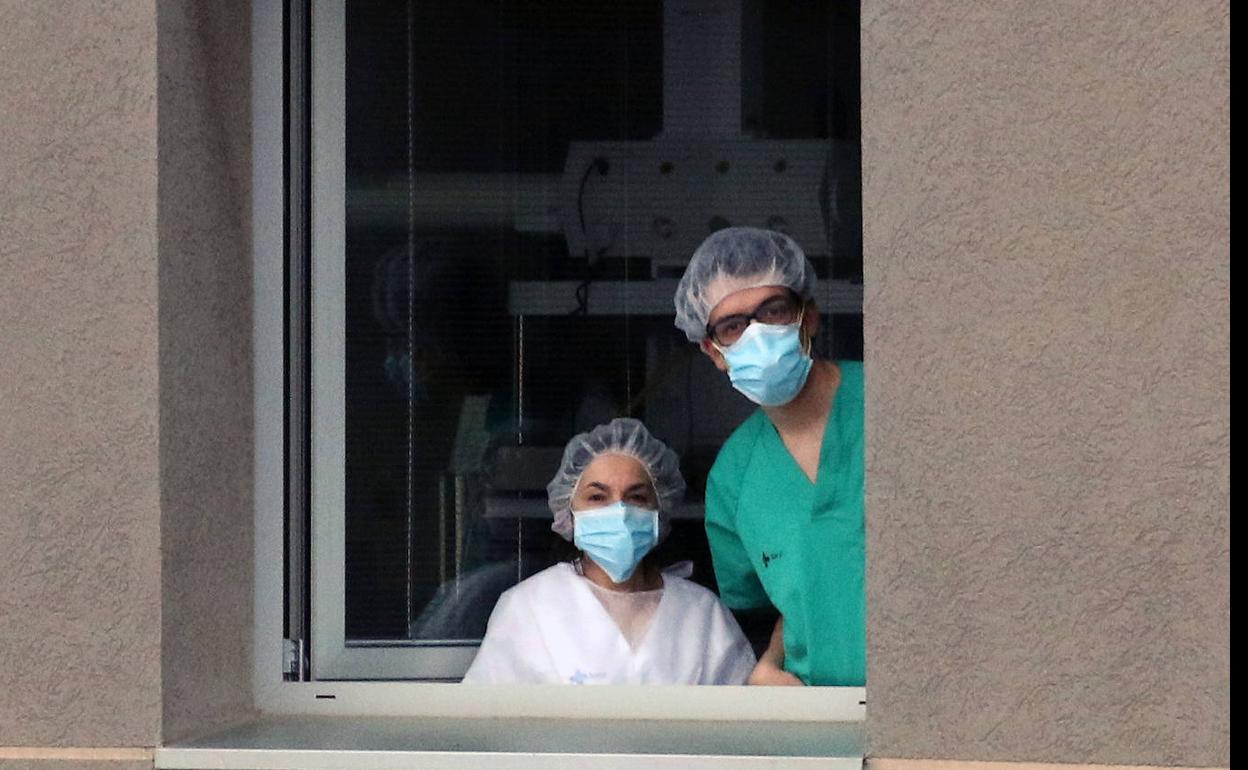 Dos trabajadores del Hospital General se asoman a una ventana. 