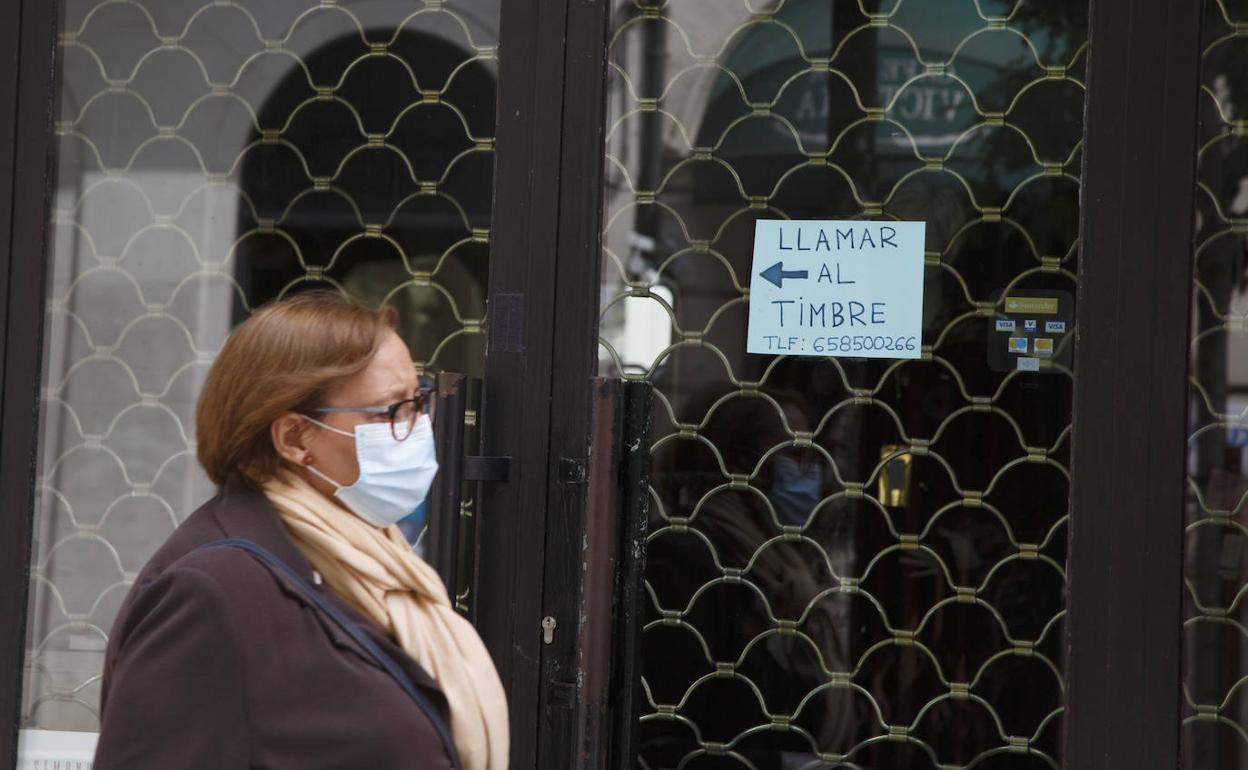 Una mujer pasa ante un comercio cerrado. 