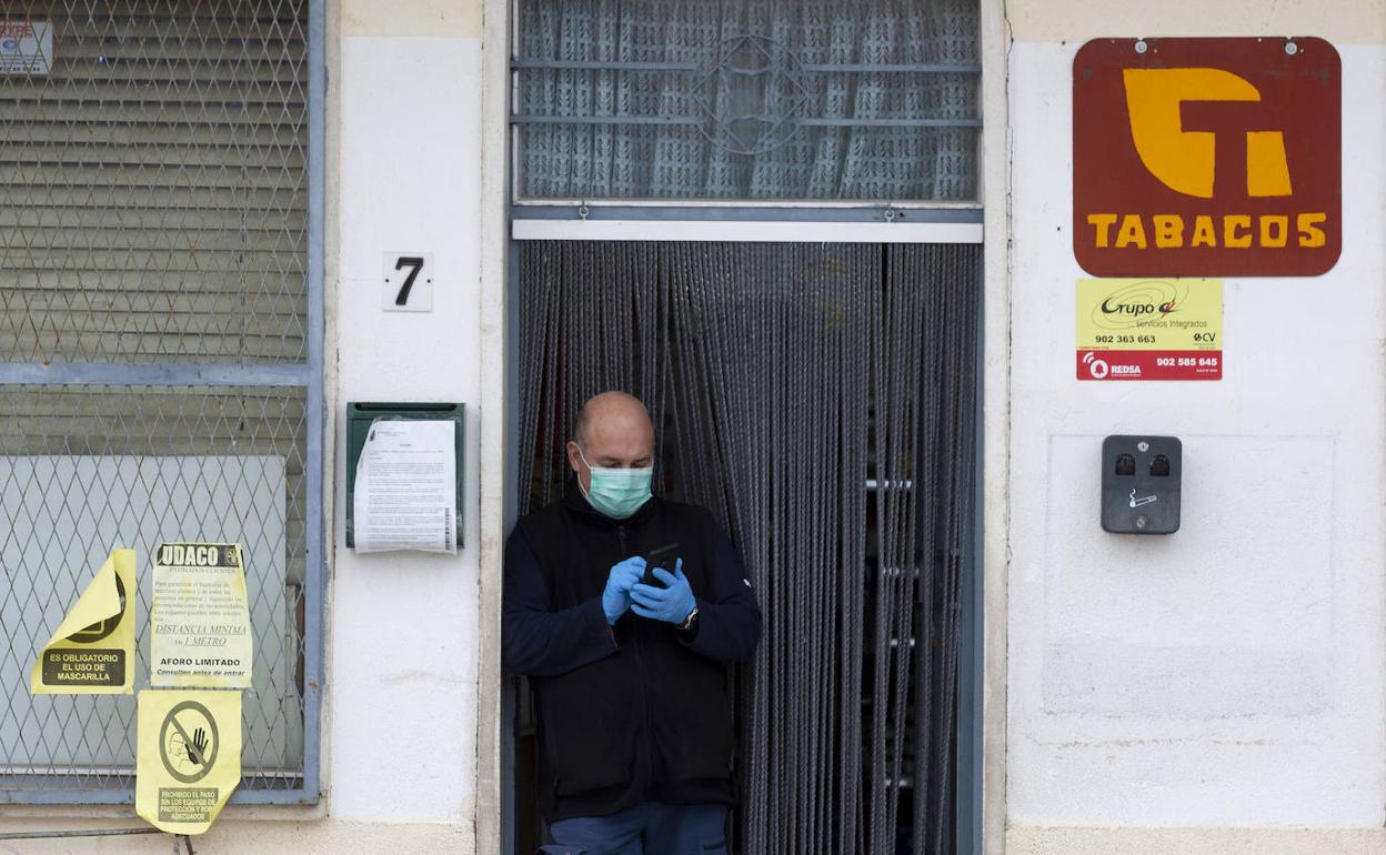 Un hombre, con guantes y mascarilla, en la puerta de un establecimiento en un municipio de Salamanca. 