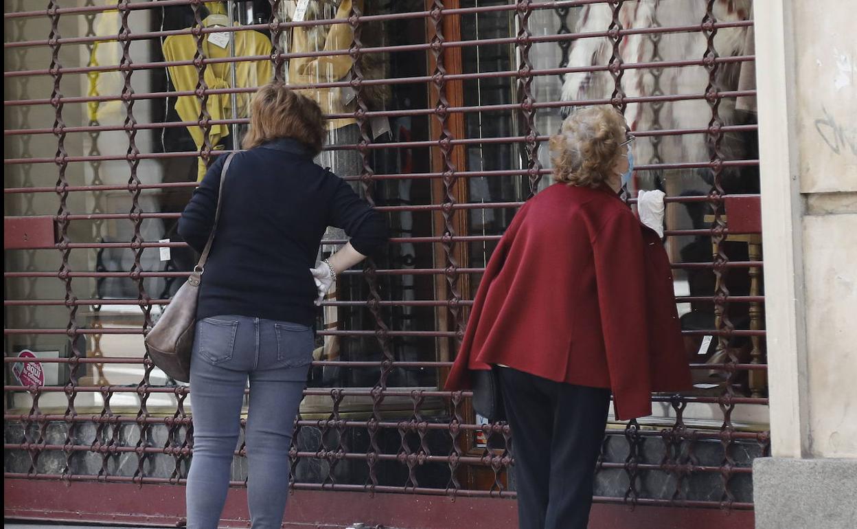 Dos mujeres observan en Palencia un comercio cerrado por la covid-19.