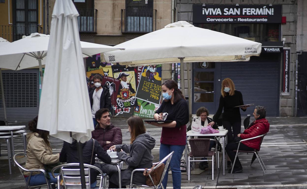 Una camarera atiende a varias personas sentadas en una terraza de Pamplona.