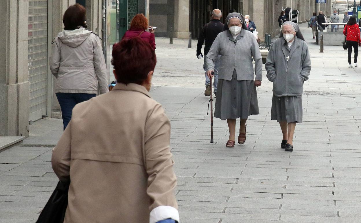 Un grupo de personas caminan por una calle de Segovia. De Torre