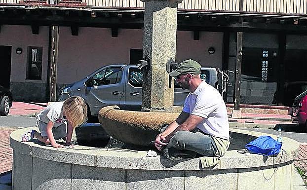 Imagen principal - Arriba, David y su hija Vega juegan en la plaza de Navafría. Abaj, Marisa, lotera de Sepúlveda, y un joven saca a a pasear a su perro por las calles desiertas de Pedraza. 