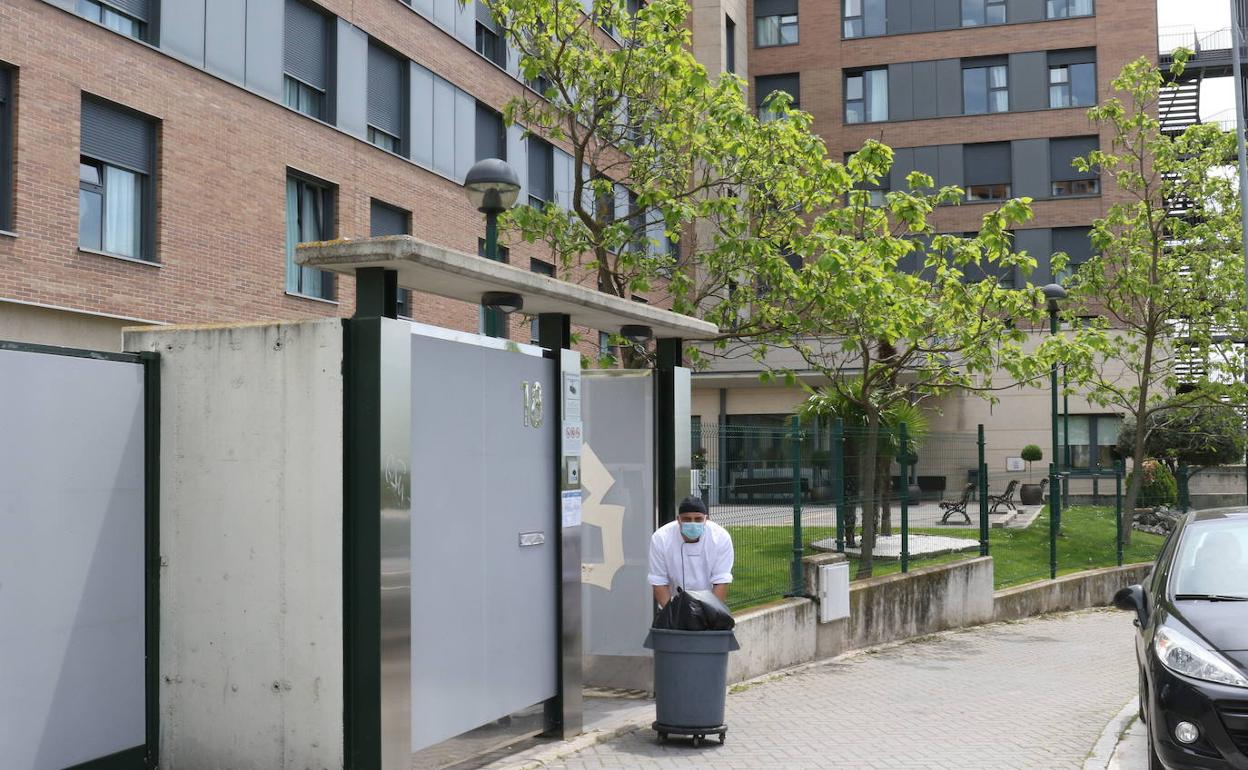 Un trabajador tira la basura en la puerta de una residencia de ancianos de Valladolid.