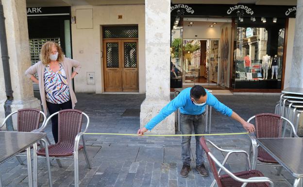 Un camarero mide la distancia entre los veladores.