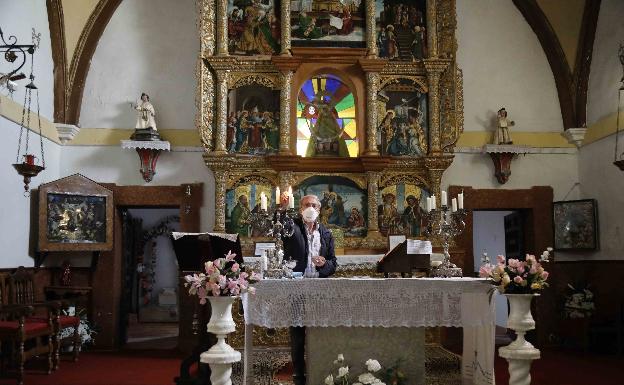 El sacerdote de la localidad enciende las velas del altar antes de la misa 