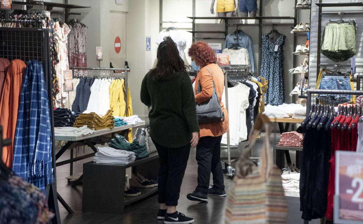 Dos mujeres miran unas prendas de ropa en una tienda de Segovia en la fase 2 de la desescalada. 