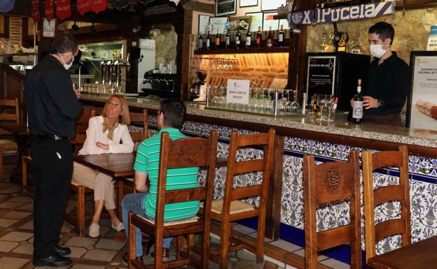 Imagen principal - Arriba y abajo a la derecha, dos clientes en una mesa y el cartel en el que se explica que la barra está fuera de servicio por el momento en Los Zagales. Abajo a la izquierda, dos ciudadanos toman unas tapas en el Bar Mini Circular. 