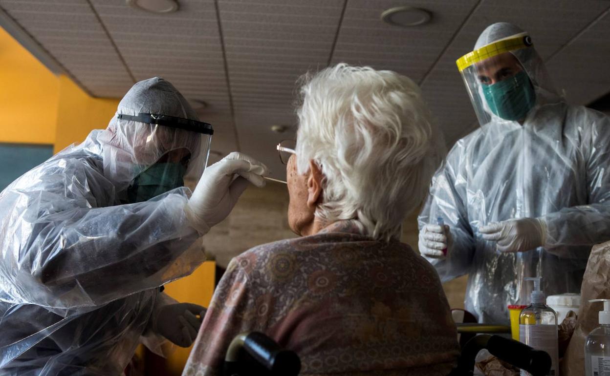 Dos sanitarios hacen un test a una mujer en una residencia. 