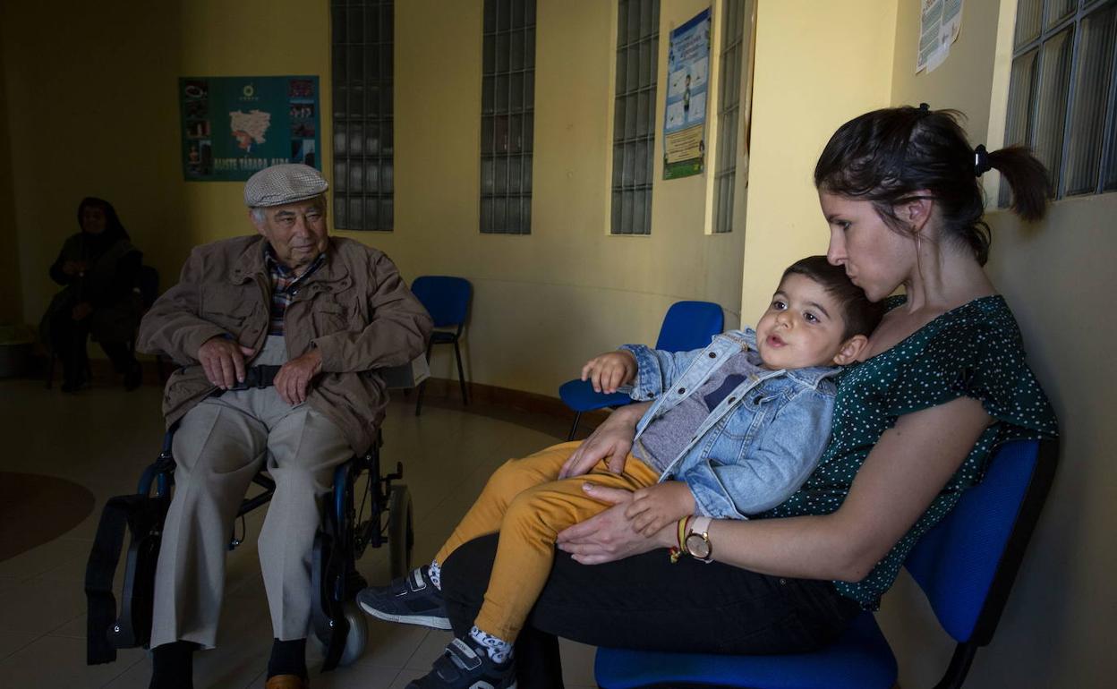 Una mujer con su hijo espera ser atendida en un consultorio rural. 