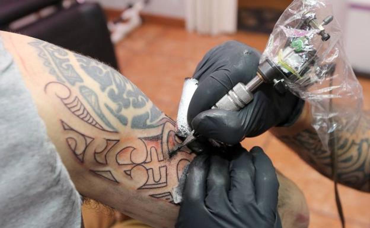 Un tatuador trabaja sobre la piel de un cliente.