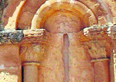 Imagen secundaria 1 - Arriba, un detalle de la puerta de la iglesia de la Natividad; Detalle de los capiteles de las columnas de una de las ventanas del ábside y espadaña con cinco huecos para campanas. 