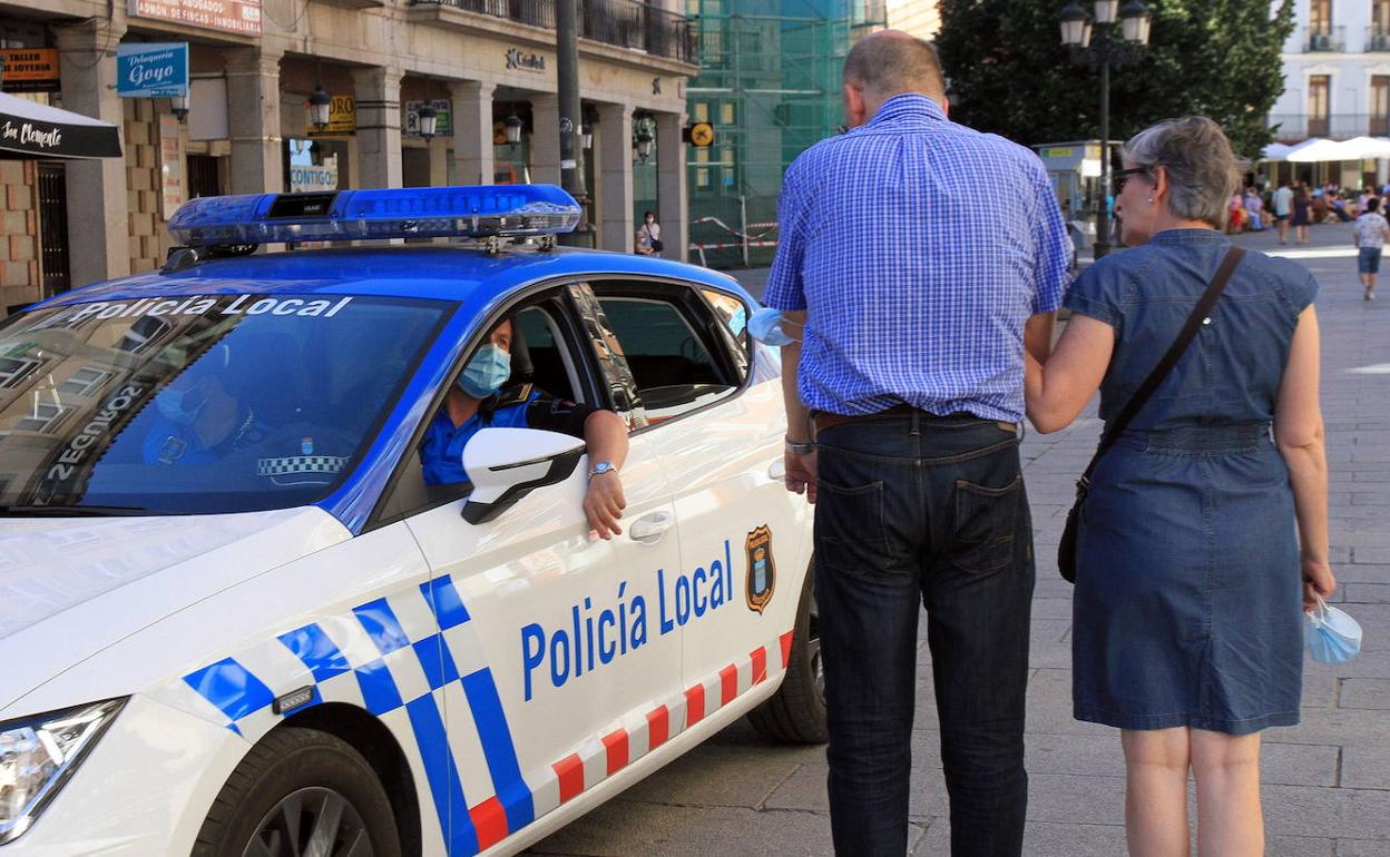Agentes de la Policía Local llaman la atención a dos personas que no tienen puesta la mascarilla. 
