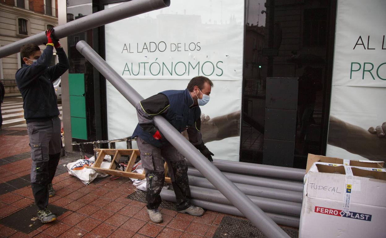 Dos operarios colocan tubos en una marquesina de Valladolid. 