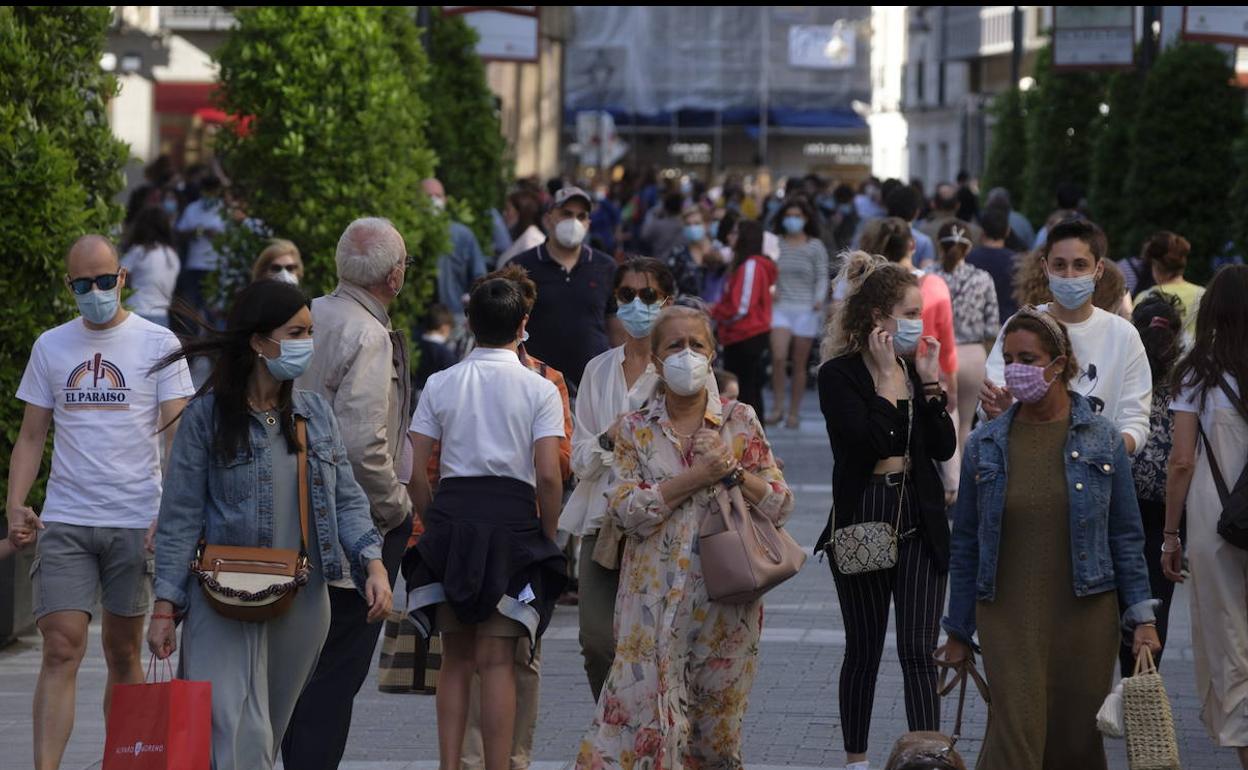 Gente con mascarilla paseando por una calle. 