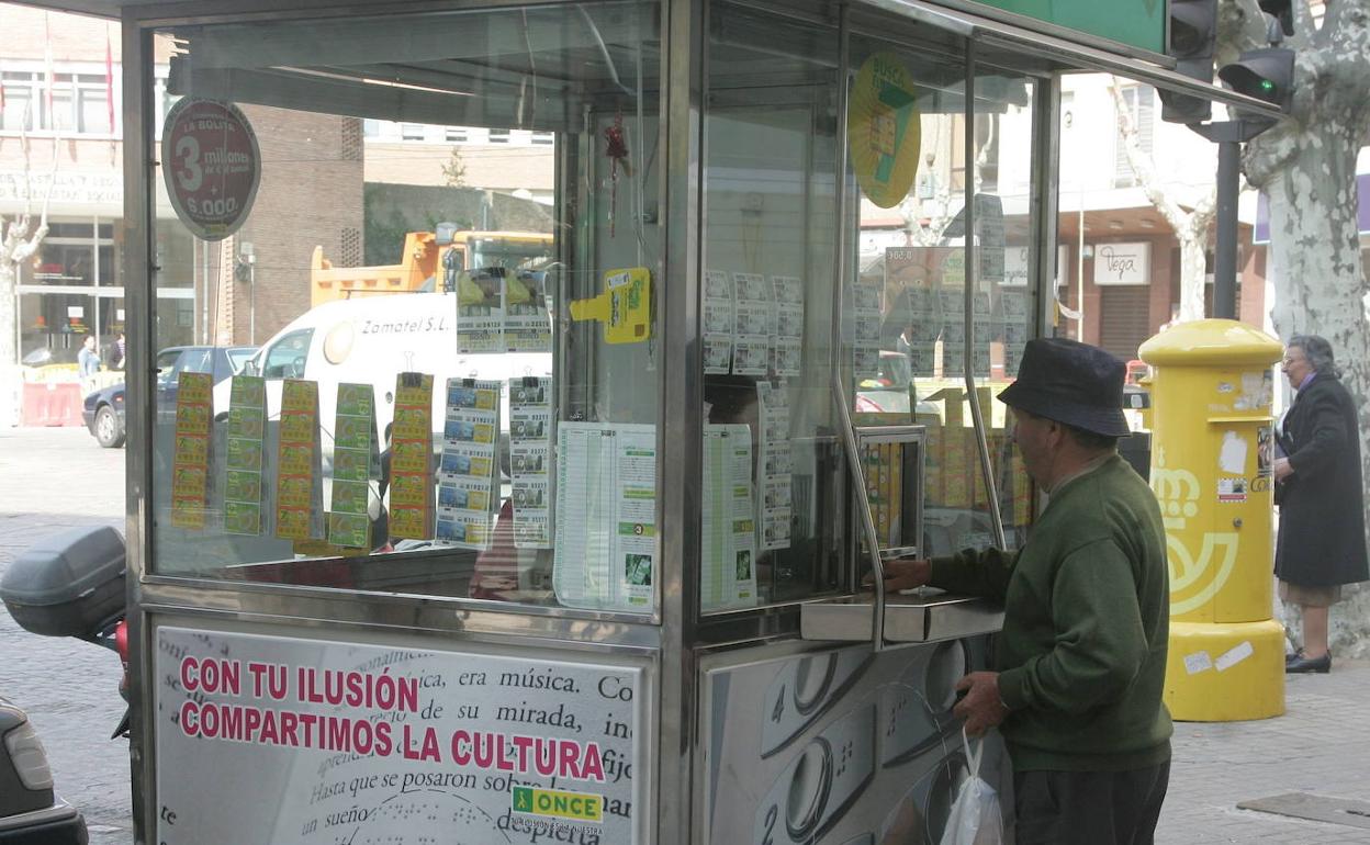 Un hombre compra un cupón en un quiosco de la ONCE . 