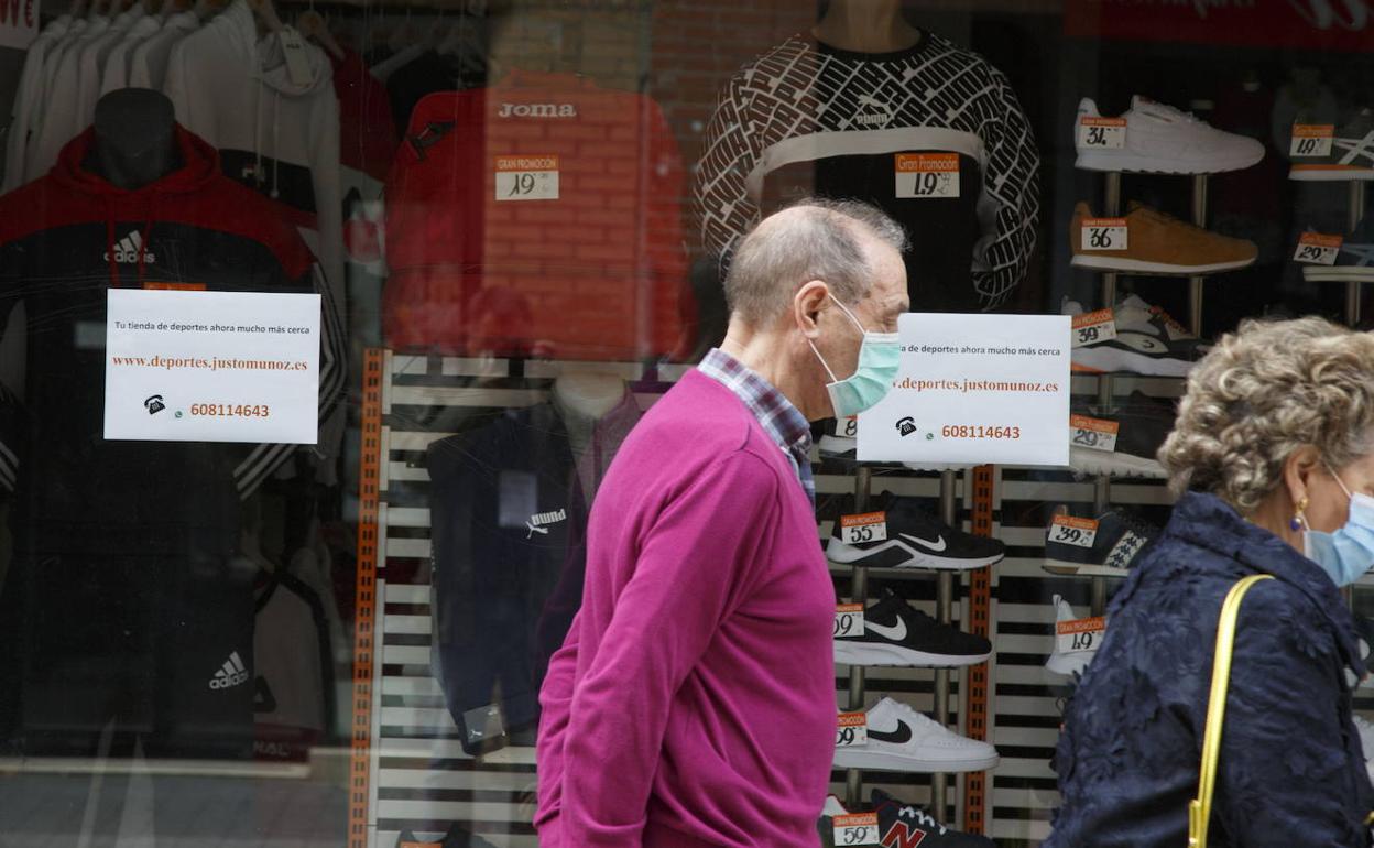 Dos vallisoletanos pasan por delante de un comercio.