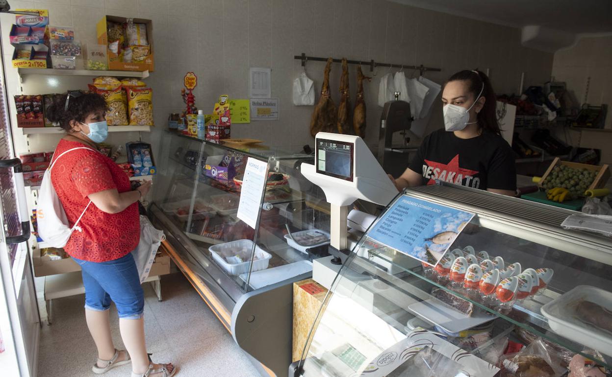 Cristina atiende a una clienta en la mañana de ayer en la tienda de alimentación que está abierta en Carrascal del Río. Óscar Costa