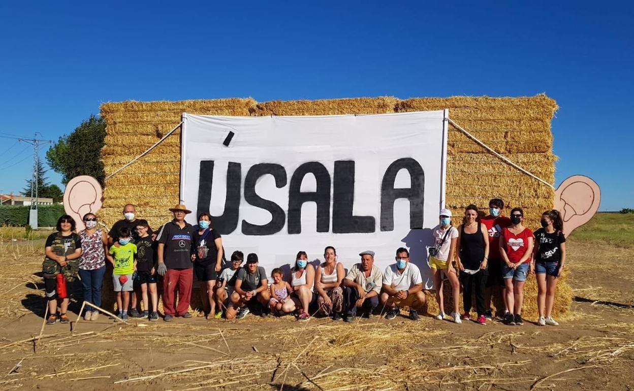 Participantes en el día del espantapájaros posan junto a la gran mascarilla. 