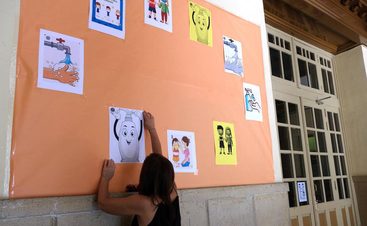 Preparación de un mural con consejos para contener el coronavirus, en el acceso al colegio García Quintana. 