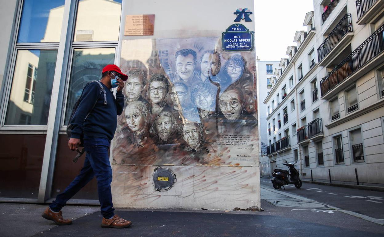 Una persna pasa delante de un cartel en París con la imagen de los diibujantes asesinados. 