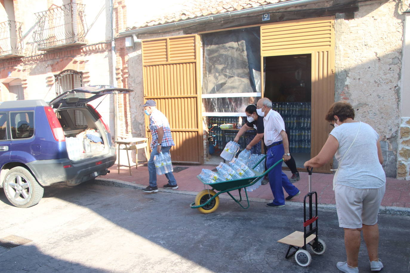 Vecinos de Lastras de Cuéllar hacen acopio de agua embotellada en un reparto anterior. 