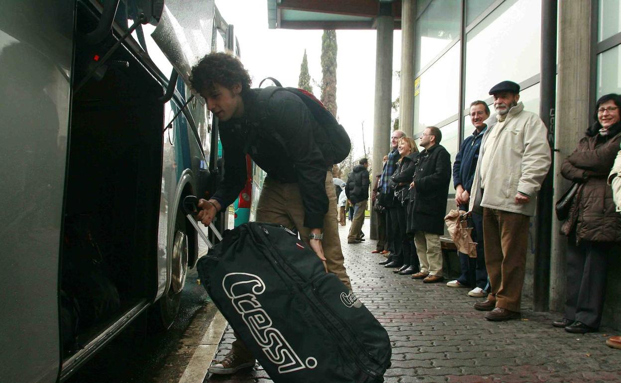 Un joven carga su equipaje en el maletero de su autobús.