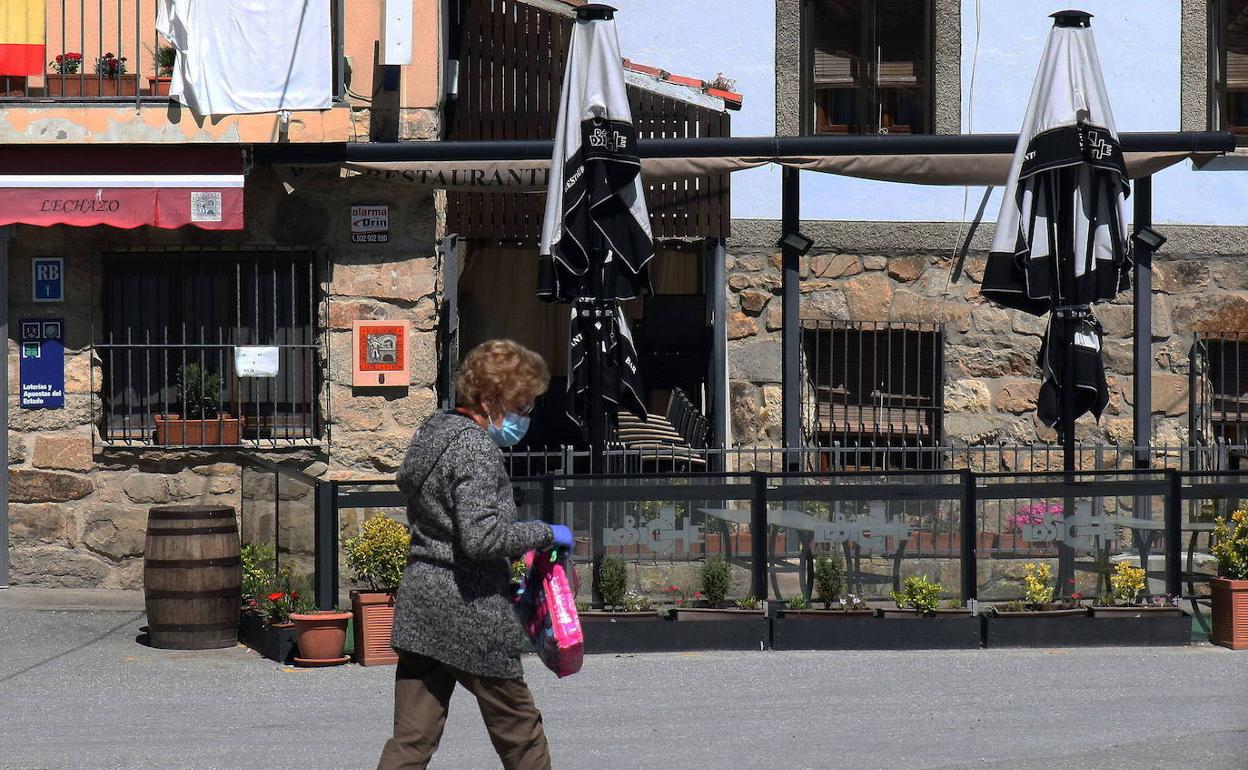 Una mujer pasa por delante del restaurante Lobiche, en Navafría, que está cerrado por vacaciones este sábado. 