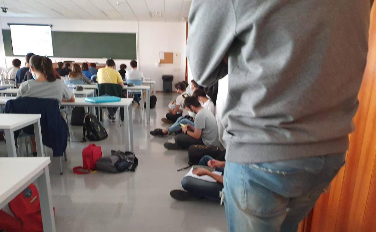 Alumnos de Física sentados en el suelo en una clase presencial debido a la mala conexión 'online'.