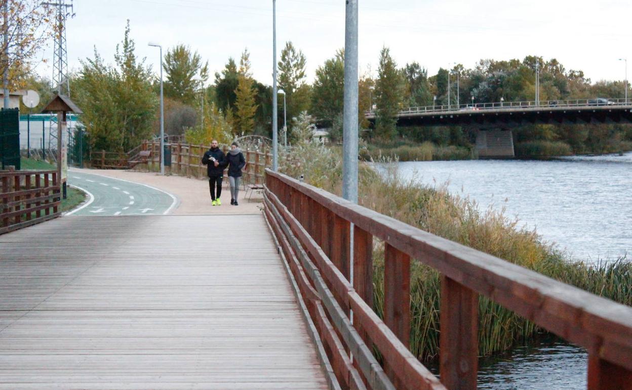 Dos personas caminan por el paseo fluvial.