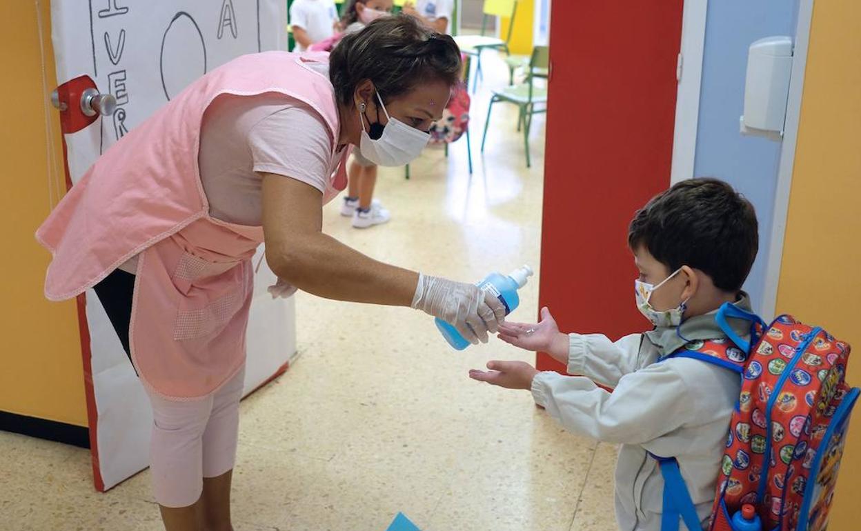 Una profesora desinfecta las manos a un niño antes de entrar en clase. 