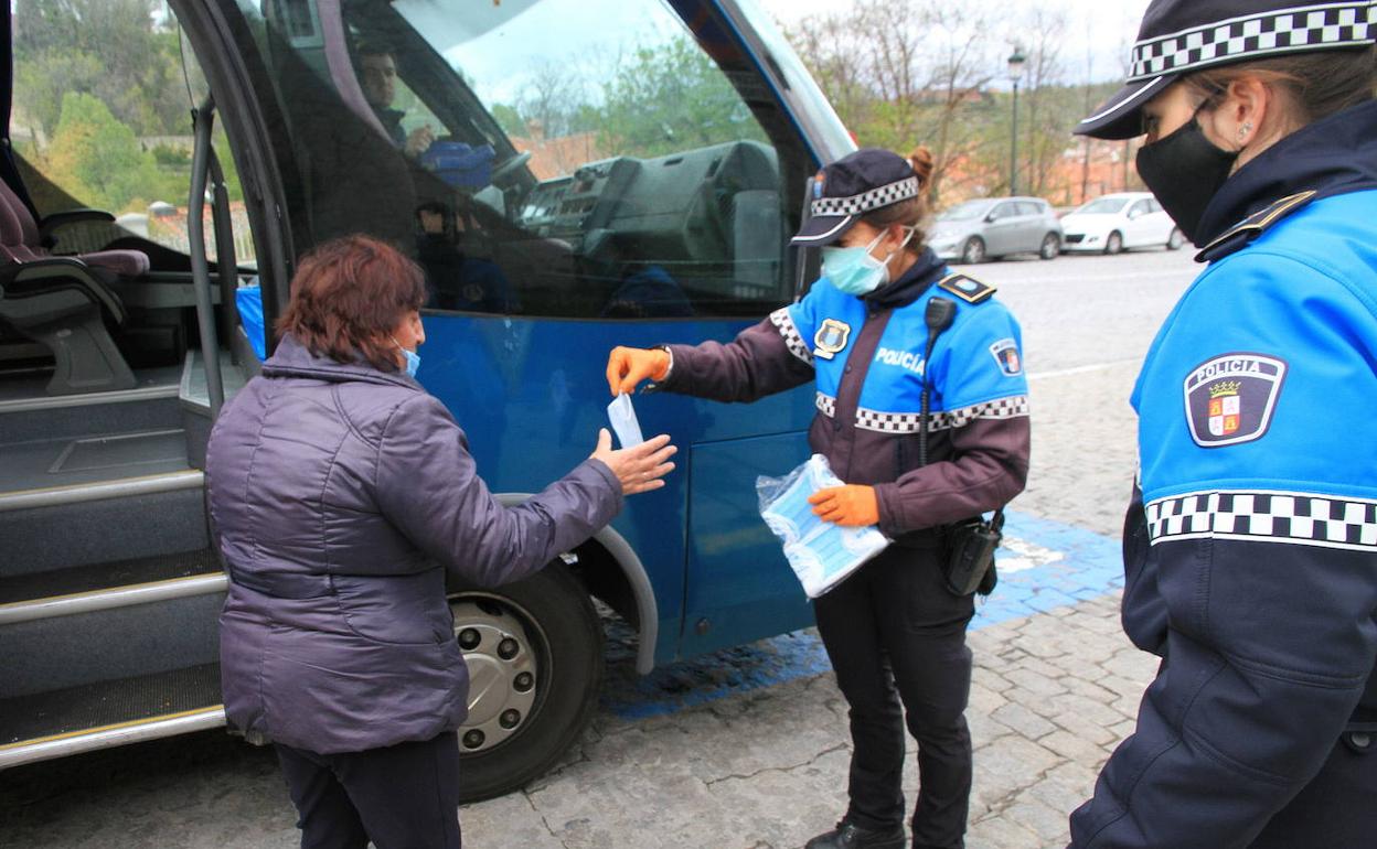 Dos agentes de la Policía Local reaparten mascarillas a usuarios del autobús durante la pandemia. 