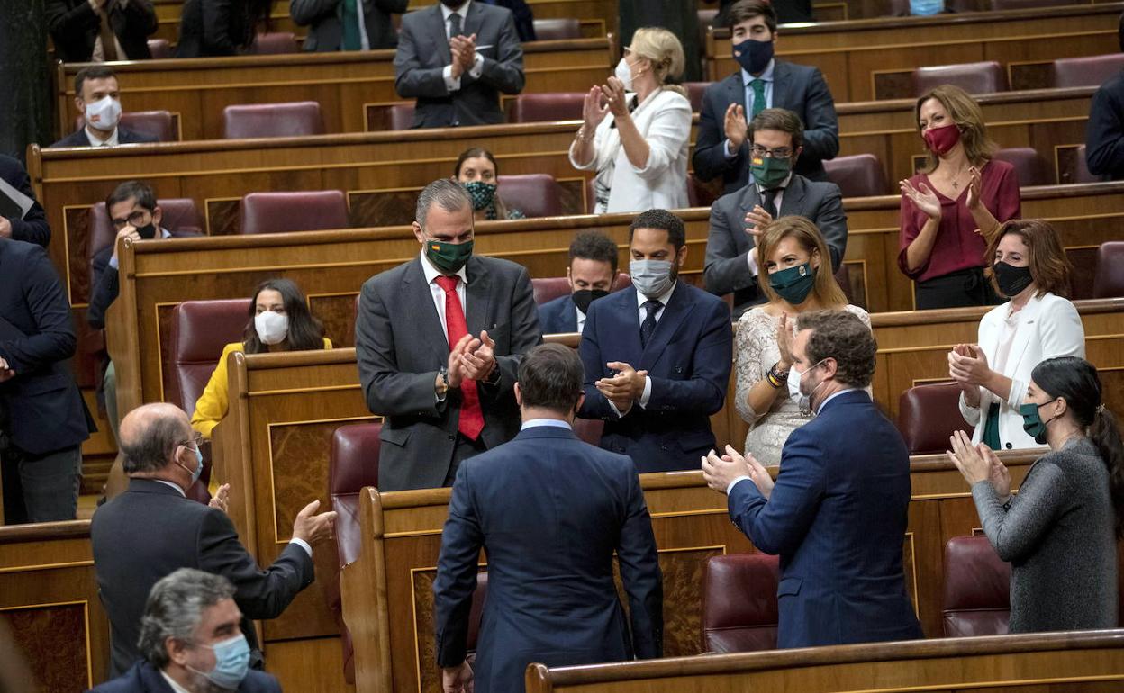 Santiago Abascal, de espaldas, es aplaudido por diputados de Vox. 