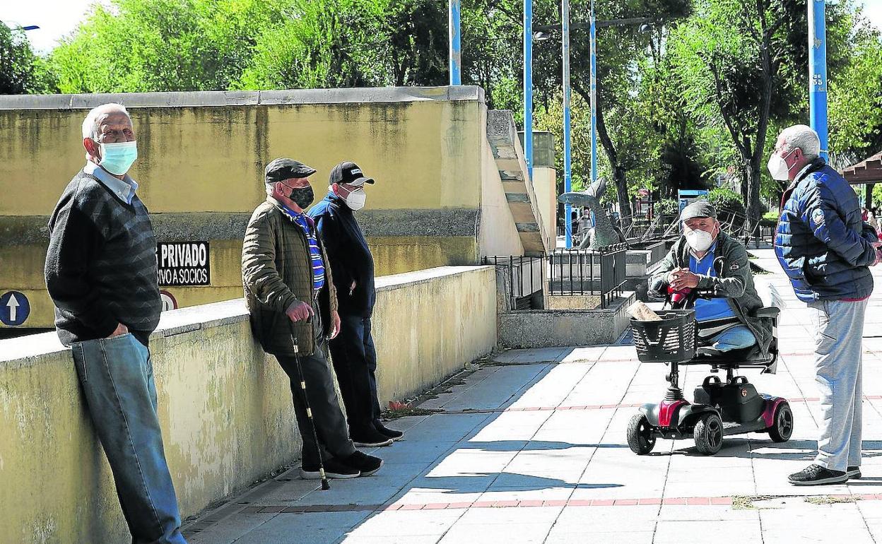 Un grupo de personas mayores mantiene la distancia de seguridad en una reunión al aire libre. 