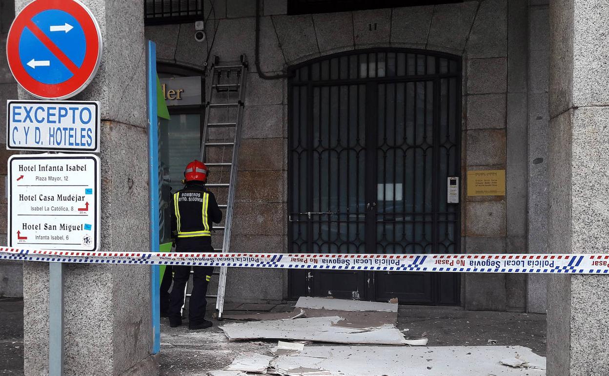 Bomberos examinan la parte afectada con las placas del techo en el suelo.